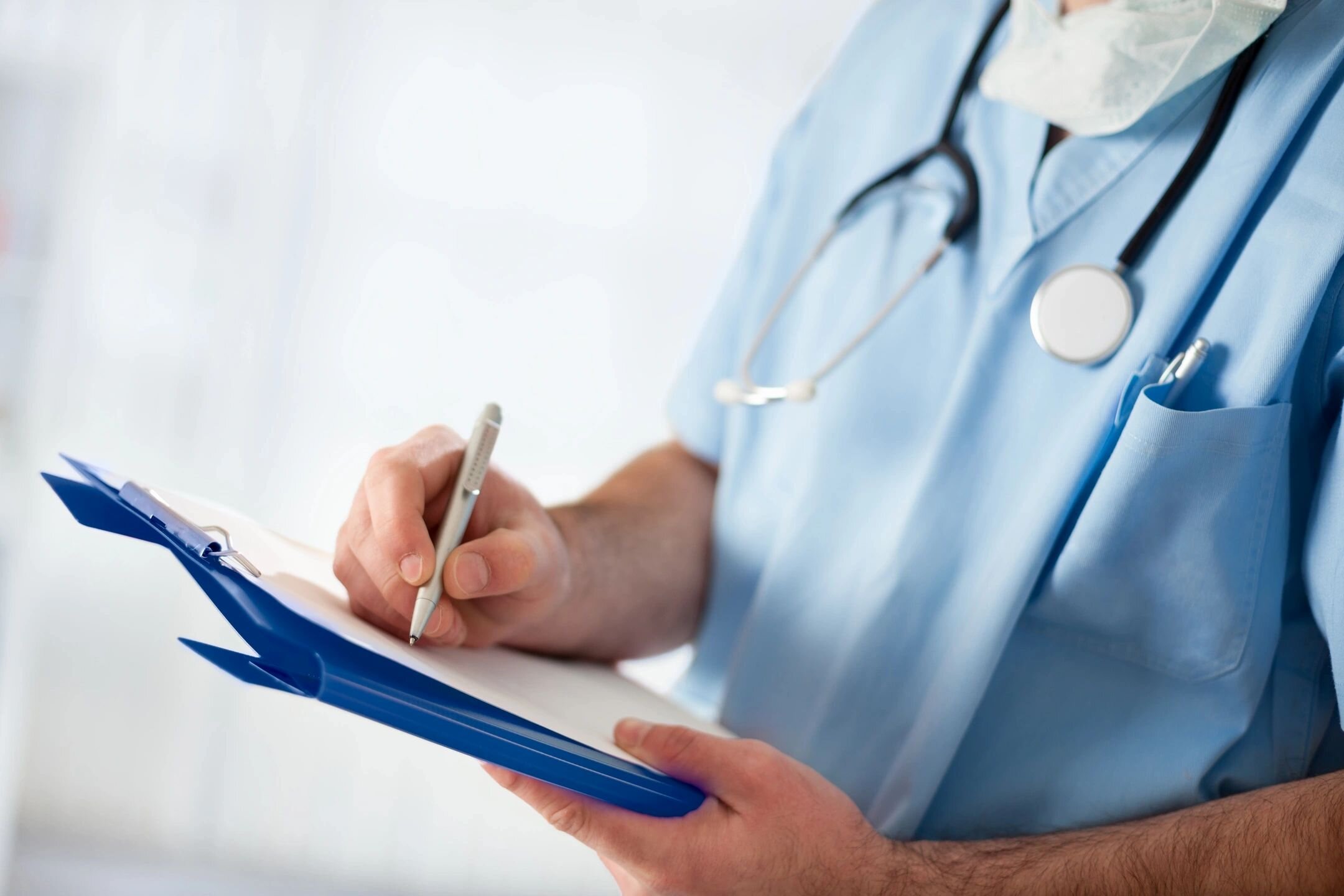 Nurse writing notes on blue clipboard